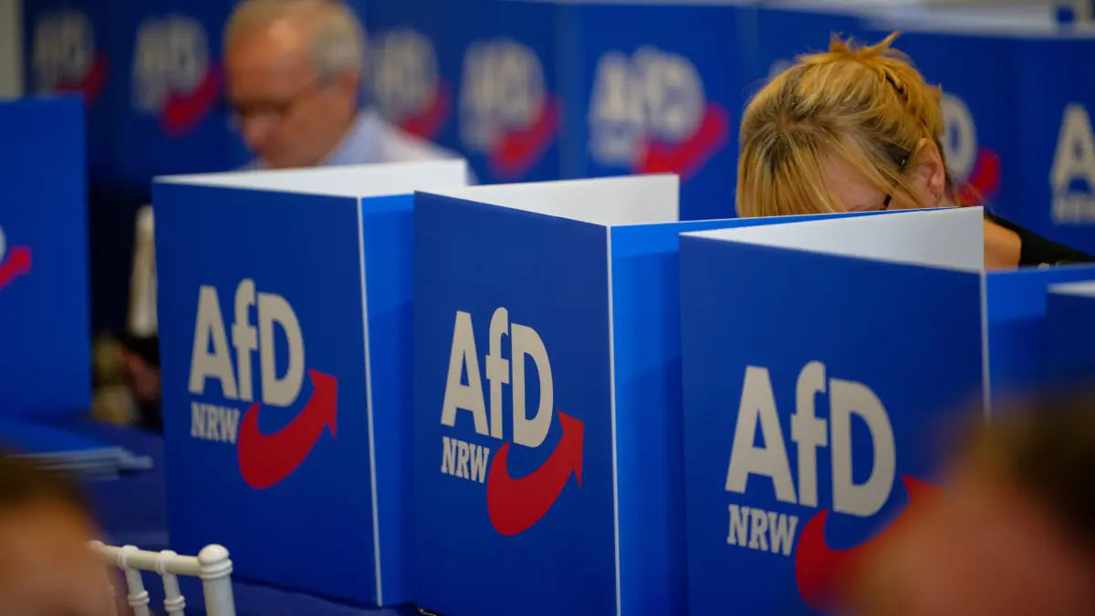 „Dann denkt sich mancher: Ich kann es ja auch einmal mit der AfD probieren. Und doch erwartet kein vernünftiger Mensch von diesem Sammelsurium ratloser Angeber auch nur die geringste Verbesserung" (Sichtschutzaufsteller stehen am 17. Juli 2026 beim Aufstellungsparteitag der AfD im nordrhein-westfälischen Marl auf den Tischen der Delegierten).