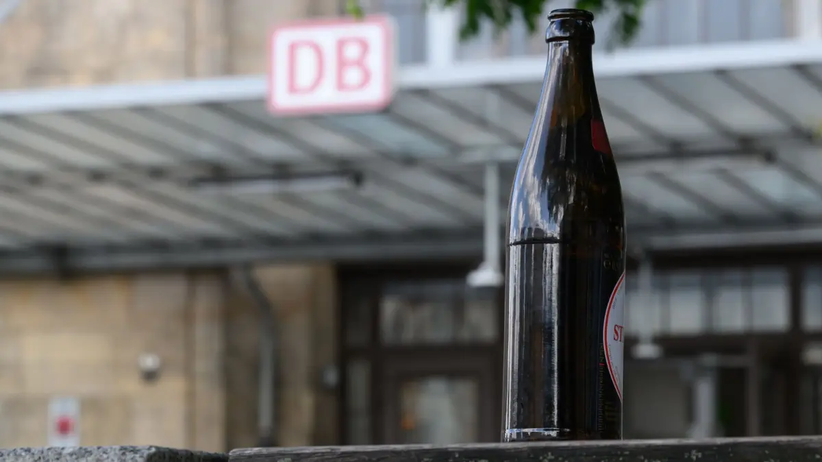 Deutsche Bahn plant Alkoholverbot an allen Bahnhöfen: 21.07.2026, Sachsen, Dresden: Eine Bierflasche steht vor dem Bahnhof Dresden Neustadt auf einer Bank. Die Deutsche Bahn plant einen radikalen Schritt mit der Hoffnung auf mehr Sicherheit für die Fahrgäste und die Beschäftigten. Foto: Robert Michael/dpa +++ dpa-Bildfunk +++