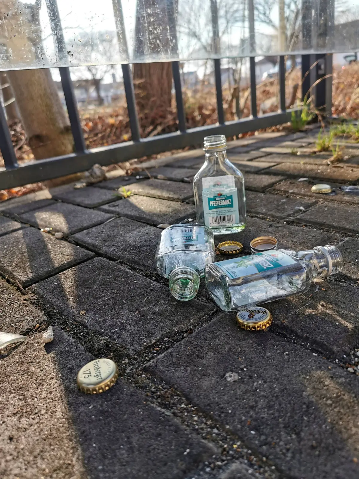 Leere Schnapsflaschen liegen an einer Haltestelle am Bahnhof Bautzen in Sachsen auf dem Bahnsteigpflaster.