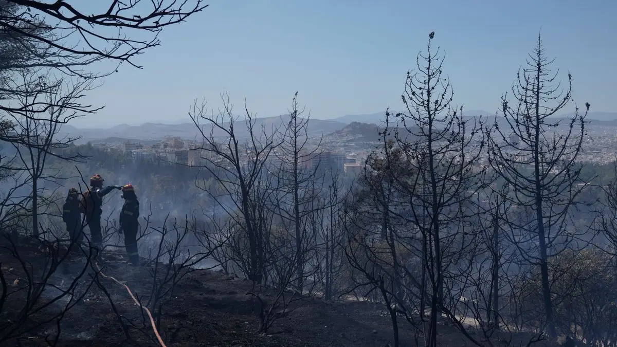 Feuerwehrleute löschen einen Flächenbrand bei Athen, Griechenland.
