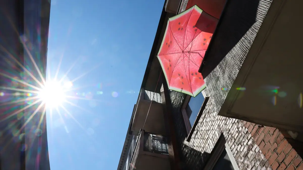Sonne in Hamburg: 29.07.2026, Hamburg: Ein Sonnenschirm in den Farben einer Wassermelone steht auf einem Balkon. Foto: Christian Charisius/dpa +++ dpa-Bildfunk +++