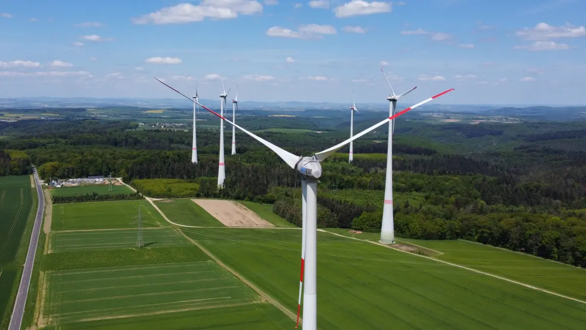 Windenergie-Ausbau in Rheinland-Pfalz: PRODUKTION - 19.05.2023, Rheinland-Pfalz, Beltheim: Windkraftanlagen mit ihren riesigen Rotorblättern ragen im Windpark bei Beltheim hinter der Elisabethmühle in die Höhe (Luftaufnahme mit einer Drohne). (zu dpa: «Antreiber oder Bremse? Grünen-Pläne zu Wind- und Solarkraft») Foto: Arne Dedert/dpa +++ dpa-Bildfunk +++