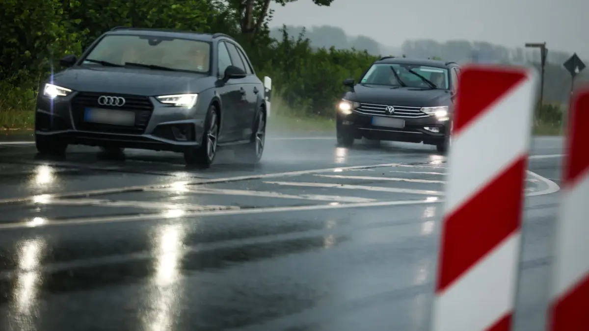 Wetter in Nordrhein-Westfalen: 30.07.2026, Nordrhein-Westfalen, Erwitte: Autos fahren mit angeschalteter Beleuchtung bei Regen über eine Landstraße. Foto: Christoph Reichwein/dpa +++ dpa-Bildfunk +++