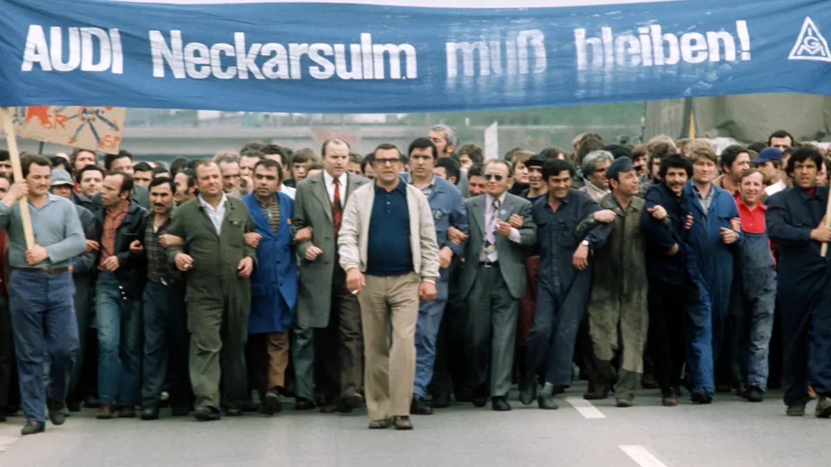 Mit einem Spruchband "Audi Neckarsulm muß bleiben" marschieren im April 1975 Arbeiter des Automobilherstellers Audi NSU untergehakt an der Spitze eines Protestmarsches auf der B 27 zwischen Neckarsulm und Heilbronn. Sie demonstrieren gegen die geplante Schließung des Automobilwerkes.