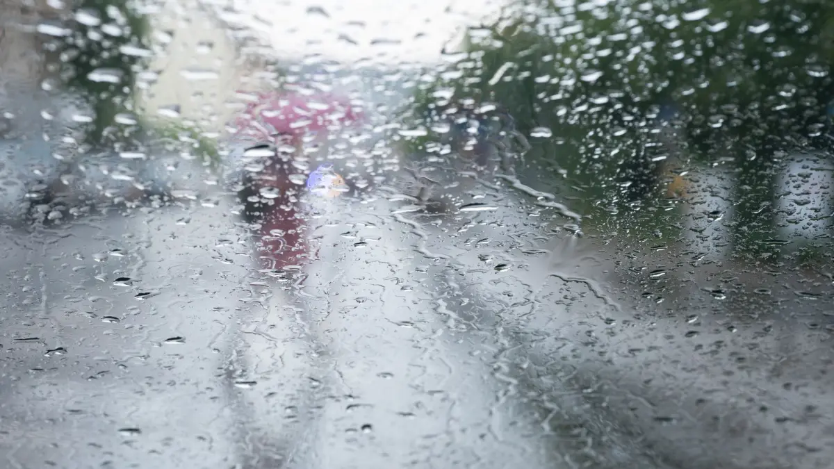 Regentropfen an Scheibe: ARCHIV - 28.07.2021, Baden-Württemberg, Stuttgart: Ein Passant geht mit einem Schirm über die Straße, aufgenommen durch eine Fensterscheibe, an der sich Regentropfen sammeln. (zu dpa: «Wetterwechsel in Sicht: Wann endlich der Regen kommen soll») Foto: Bernd Weissbrod/dpa +++ dpa-Bildfunk +++