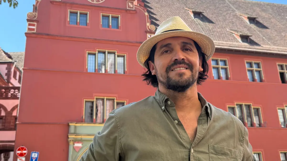 „Coolcation“ im Schwarzwald: ARCHIV - 12.08.2026, Baden-Württemberg, Freiburg im Breisgau: Stadtführer Cardenio Vásquez Avilés steht auf dem Rathausplatz in Freiburg. Er bietet ausschließlich Führungen auf Spanisch an, die ihm zufolge insbesondere im Sommer gut besucht sind. (zu dpa: ««Coolcation»-Trend: Schwarzwald lockt mehr Südeuropäer an») Foto: Magdalena Henkel/dpa +++ dpa-Bildfunk +++