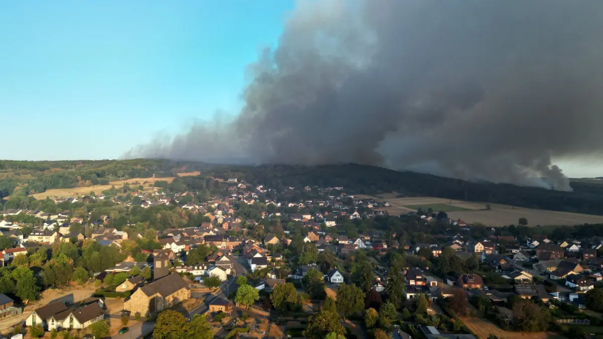 Rauch eines Waldbrands im Hürtgenwald zieht über den Ortsteil Gey: Rauch eines Waldbrands zieht über den Ortsteil Gey: Wenn das eigene Haus durch die Flammen Schaden nimmt, können Eigentümerinnen und Eigentümer auf ihre Wohngebäudeversicherung bauen. (zu dpa: «Welche Versicherung zahlt bei Schäden durch Waldbrand?») Foto: Federico Gambarini/dpa/dpa-mag - Honorarfrei nur für Bezieher des Dienstes dpa-Magazin +++ dpa-Magazin +++