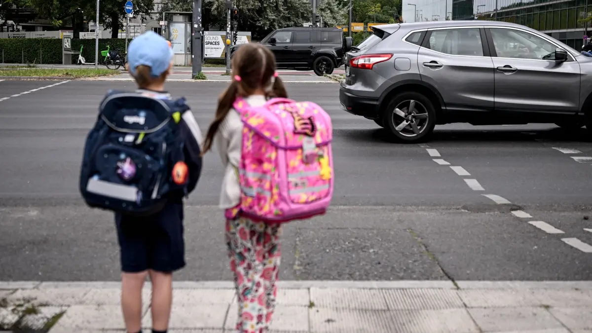 Erster Schultag in Berlin und Brandenburg: 24.08.2026, Berlin: Die Schulanfänger Edgar (6) und Angelina (5) stehen an einer Straße am Rande der Schulanfangskampagne „Achtung Schulweg! Sicher starten, sicher ankommen“. Die Kampagne macht auf die besondere Situation von Kindern im Straßenverkehr aufmerksam und wirbt für mehr Rücksicht und Aufmerksamkeit. Foto: Britta Pedersen/dpa +++ dpa-Bildfunk +++