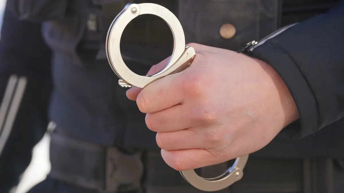 Polizei Handschellen - Symbolbild: ARCHIV - 18.01.2024, Mecklenburg-Vorpommern, Schwerin: Ein Polizist hält Handschellen in der Hand. (zu dpa: «Ehefrau gewürgt und mit Messer verletzt - Mann in U-Haft») Foto: Marcus Brandt/dpa +++ dpa-Bildfunk +++