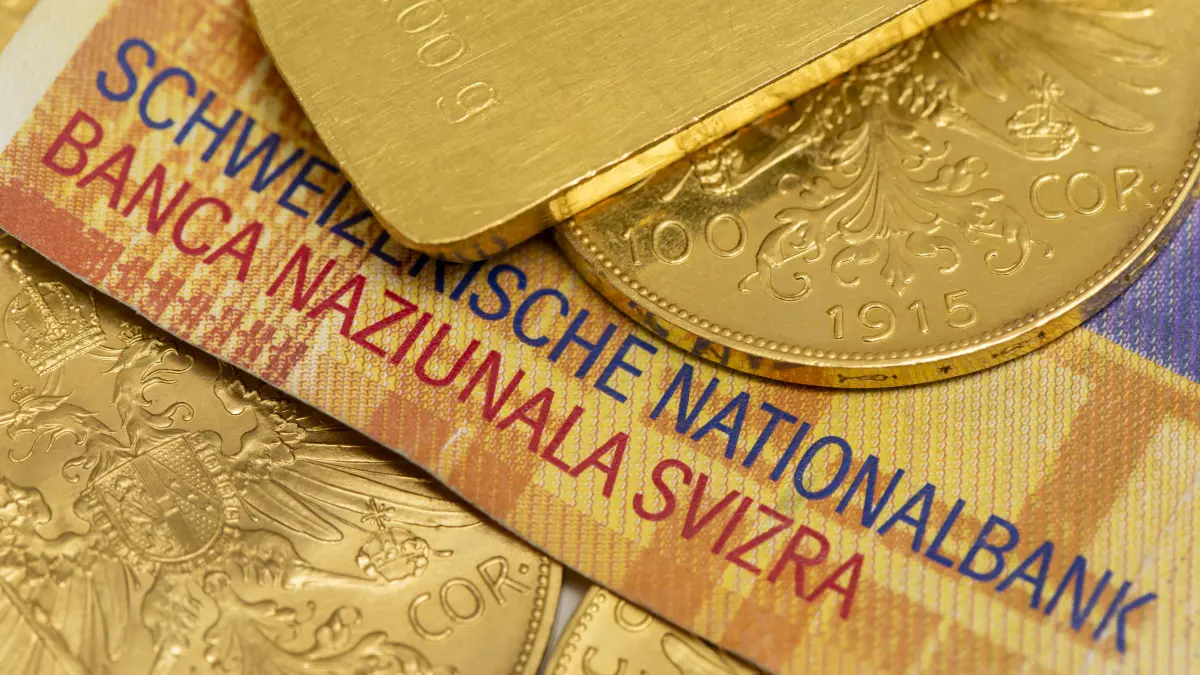 Goldpreis und Goldanlage Goldmünzen liegen auf Schweizer-Franken-Geldscheinen, als Symbolbild für krisensichere und währungsunabhängige Geldanlage in Edelmetall - NUR FÜR REDAKTIONELLE VERWENDUNG - *** Gold Prices and Gold Investments: Gold coins are depicted on Swiss franc banknotes as a symbolic representation of a crisis-proof and currency-independent investment in precious metals. FOR EDITORIAL USE ONLY