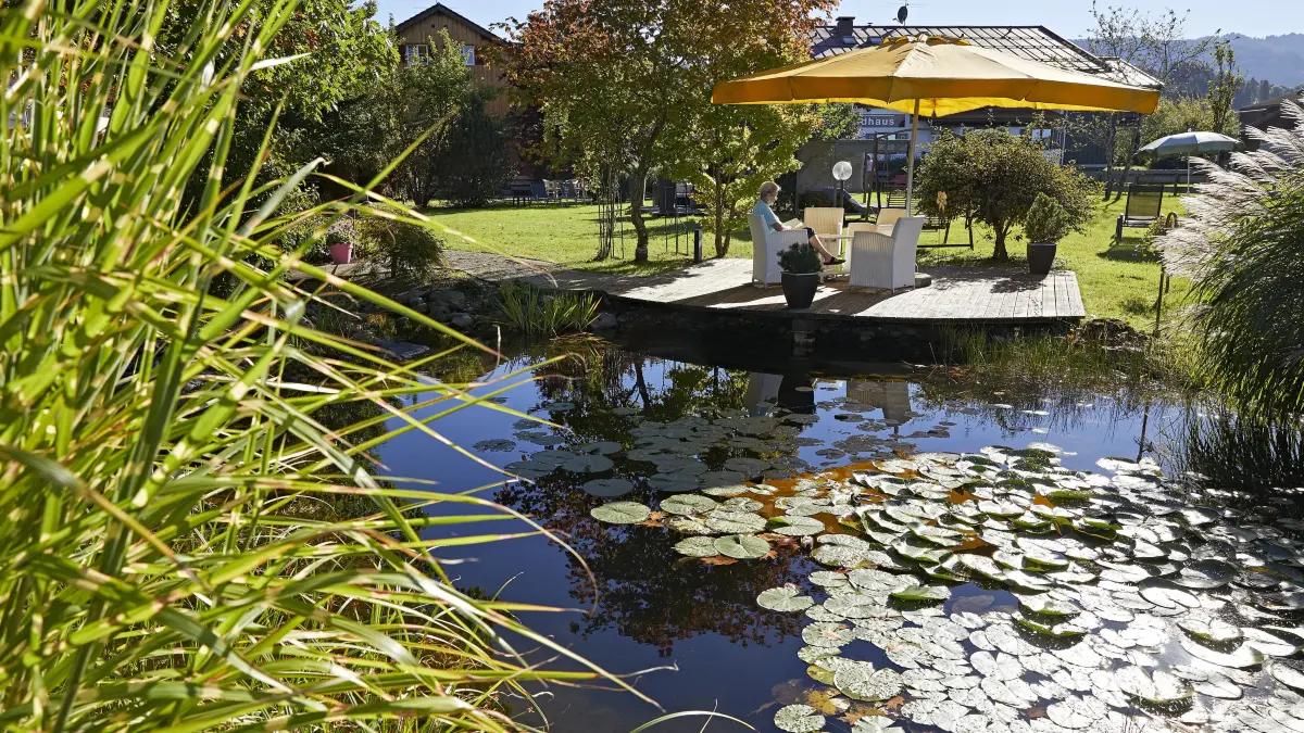 Sonnige Idylle am Teich: Der Hotelgarten im Herbst lädt zum Entspannen ein.