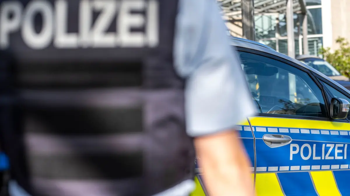Symbolbild - Blaulicht: Ein Polizist steht vor einem Streifenwagen. Ermittler der Kriminalpolizei in Köln haben bei der Wohnungsdurchsuchung eines unter Verdacht geratenen Altenpflegers mutmaßliches wertvolles Diebesgut entdeckt. (zu dpa: «Falsche Ärzte erbeuten sechsstellige Summe»)