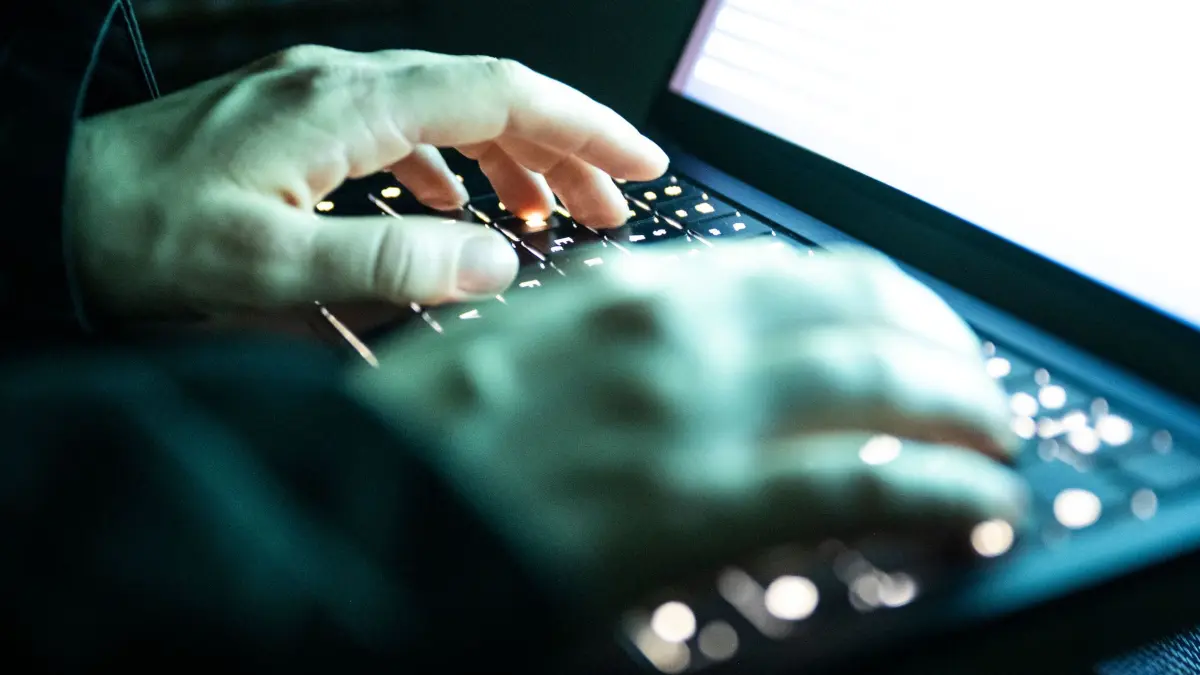 Cyberkriminalität: ILLUSTRATION - 14.12.2025, NA, Berlin: Eine Person tippt mit den Fingern auf einer beleuchteten Laptop-Tastatur.(gestellte Szene) (zu dpa: «Cyberangriff auf städtischen Betrieb in Kassel») Foto: Philip Dulian/dpa +++ dpa-Bildfunk +++