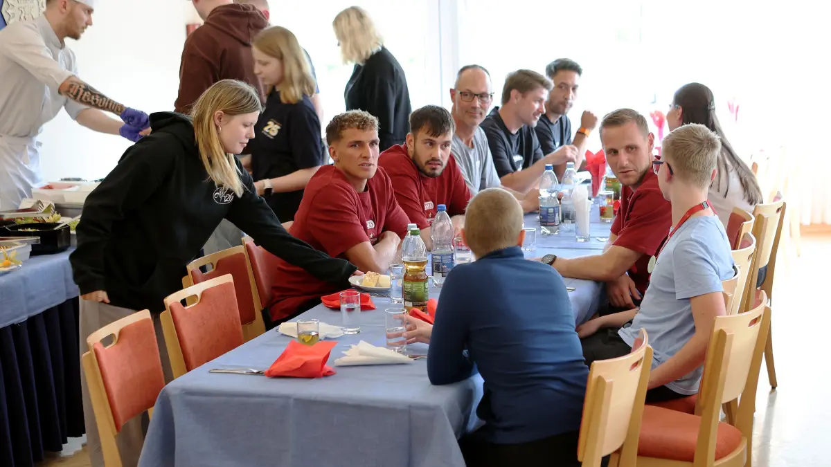 VfB Stuttgart Nachsorgeklink Tannheim: BAU // Deutschland, 29.09.2026, Tannheim, VfB Stuttgart zu Besuch in der Nachsorgeklink Tannheim, gemeinsames Essen, v.l. Grischa Prömel, Stefan Drljaca und Marius Funk am Tisch mit den KIndern und Jugendlichen
