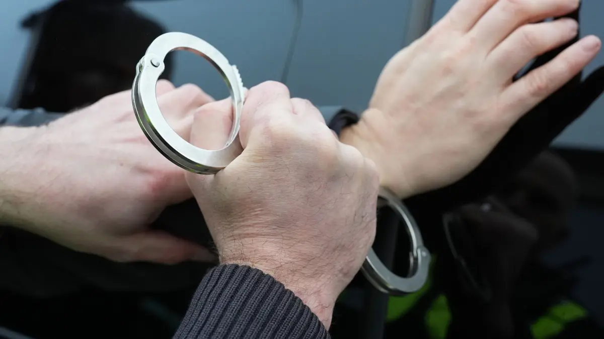 Festnahme Symbolbild: ARCHIV - 11.12.2024, Schleswig-Holstein, Kiel: Ein Polizist legt einem Mann Handschellen an. (Symbolfoto) (zu dpa: «Masche mit Goldankauf - Polizei nimmt fünf Verdächtige fest») Foto: Marcus Brandt/dpa +++ dpa-Bildfunk +++