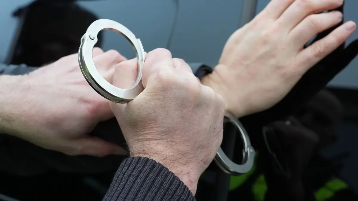 Festnahme Symbolbild: Ein Polizist legt einem Mann Handschellen an. (Symbolfoto) (zu dpa: «Masche mit Goldankauf - Polizei nimmt fünf Verdächtige fest»)