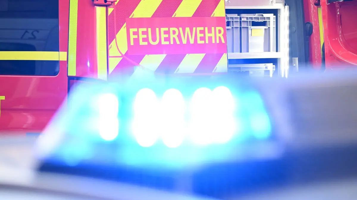 Feuerwehr Symbolbild: Ein Fahrzeug der Feuerwehr steht bei einem Einsatz auf einer Straße, während im Vordergrund das Blaulicht eines Polizeifahrzeugs zu sehen ist. (zu dpa: «A2 nach Unfällen Richtung Berlin gesperrt – neun Verletzte»)