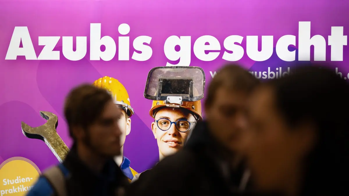 Ausbildungsmarkt: ARCHIV - 19.01.2024, Sachsen, Dresden: Besucher stehen auf einer Jobmesse vor dem Schriftzug «Azubis gesucht». (zu dpa: «DGB will mehr Ausbildungsplätze: Betriebe sollen zahlen») Foto: Sebastian Kahnert/dpa +++ dpa-Bildfunk +++