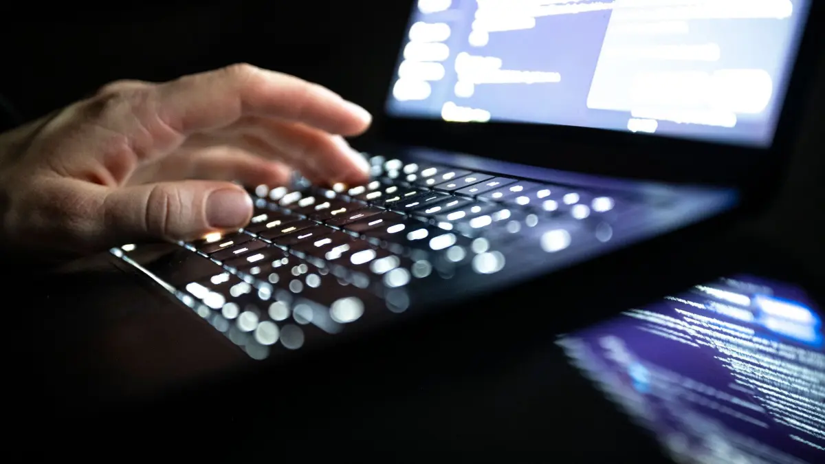 Cyberkriminalität: ILLUSTRATION - 14.12.2025, NA, Berlin: Eine Person tippt mit den Fingern auf einer beleuchteten Laptop-Tastatur.(gestellte Szene) (zu dpa: «Junge Hacker aus Europa messen sich in Hacker-Challenge») Foto: Philip Dulian/dpa +++ dpa-Bildfunk +++