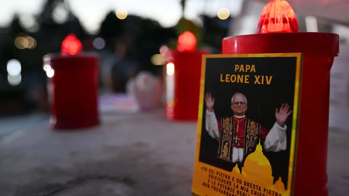 VATICAN-POPE-RELIGION-HEALTH: A picture of Pope Leo XIV and candles are laid at the statue of John Paul II outside the Gemelli University Hospital, where Pope Leo XIV is recovering after undergoing surgery to remove a cancerous tumour from his right lung, in Rome on October 14, 2026. (Photo by Tiziana FABI / AFP)