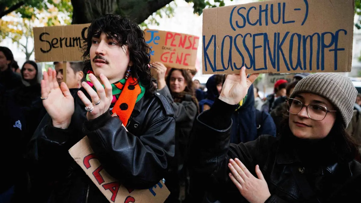 Demonstration „Solidarität mit den Schüler:innen in Frankreich“: 17.10.2026, Berlin: Teilnehmer halten Schilder mit verschiedenen Texten in französcher und deutscher Sprache, darunter mit der Aufschrift "(Schul-) Klassenkampf" bei der Demonstration "Solidarität mit den Schüler:innen in Frankreich". In Frankreich gehen seit Ende September Schülerinnen, Schüler und Studierende zu Hunderttausenden auf die Straße. Sie fordern unter anderem eine bessere Ausstattung der Schulen, mehr Lehrkräfte und bessere Lernbedingungen. Foto: Carsten Koall/dpa +++ dpa-Bildfunk +++