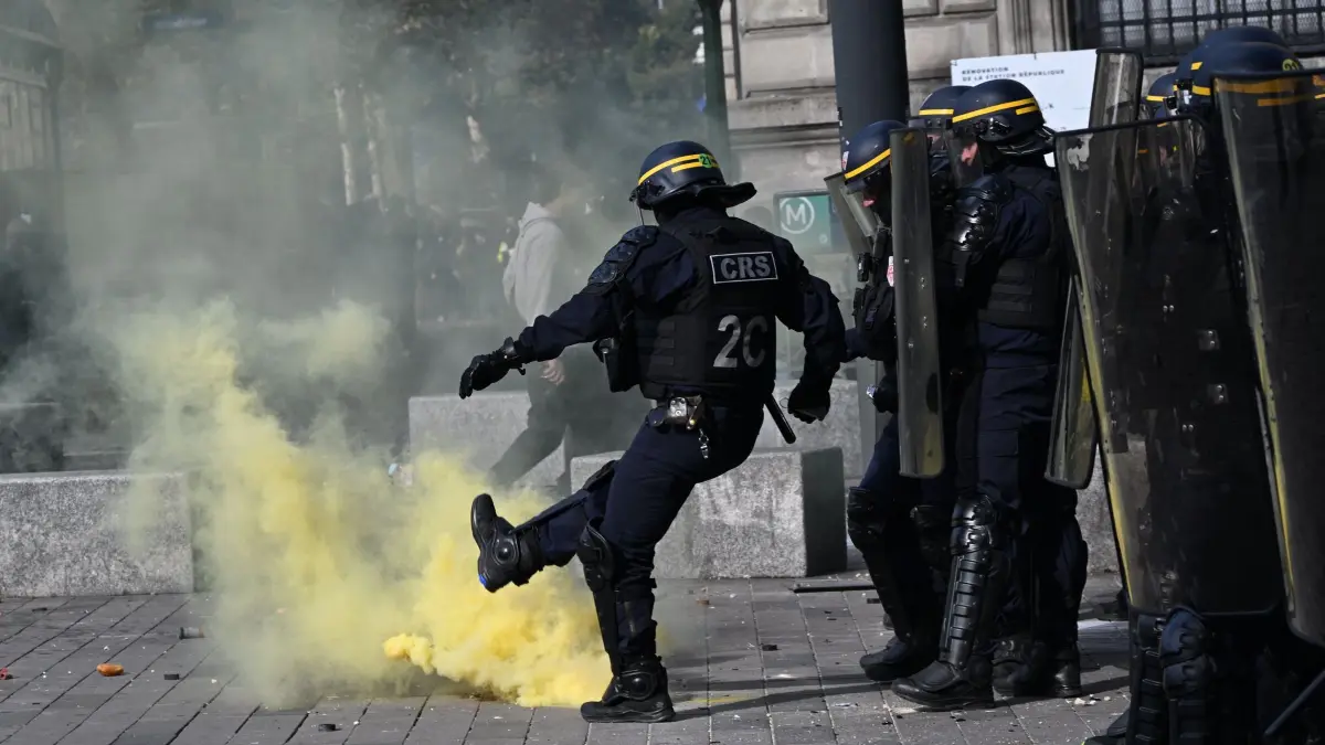 Protesttag in Frankreich: Ein Polizist tritt gegen eine Tränengasgranate, während Demonstranten gegen steigende Lebenshaltungskosten protestieren und sich damit den Forderungen der Schüler anschließen. (zu dpa: ««Wir haben die Schnauze voll!» - Neue Proteste in Frankreich»)