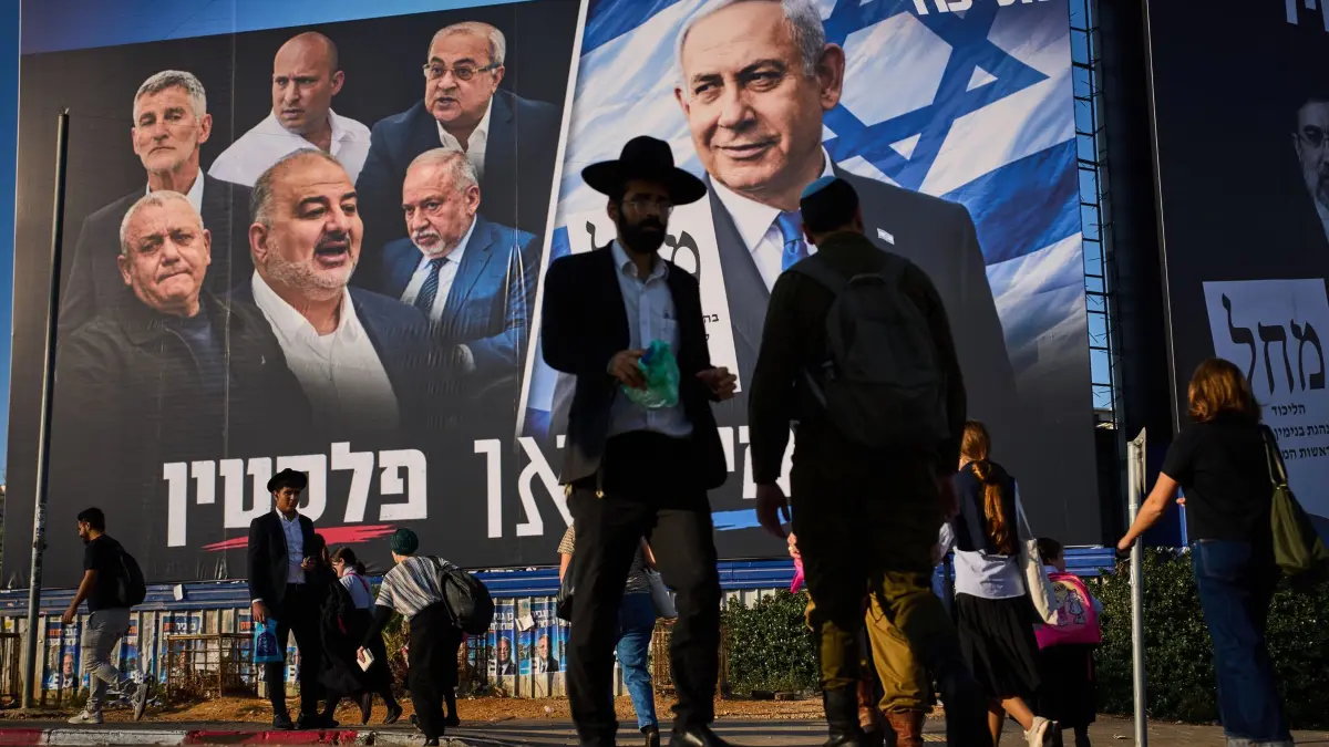 Vor den Parlamentswahlen in Israel: 18.10.2026, Israel, Bnei Brak: Im Vorfeld der Parlamentswahlen in Israel gehen Menschen an einer Wand mit Wahlplakaten der Likud-Partei vorbei, auf der der israelische Ministerpräsident Benjamin Netanjahu neben den Vorsitzenden der Oppositionsparteien zu sehen ist und die den hebräischen Slogan „Rechts oder Palästina“ trägt. Foto: Oded Balilty/AP/dpa +++ dpa-Bildfunk +++