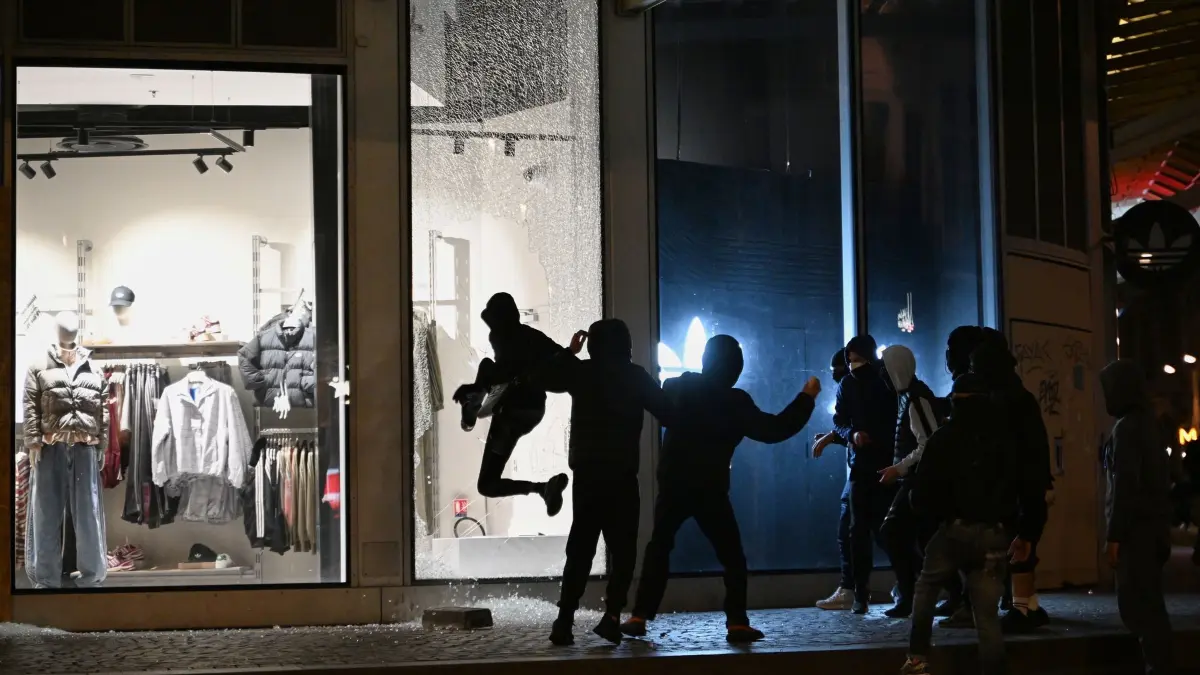 Proteste in Frankreich: Jugendliche zerschlagen bei Zusammenstößen zwischen Demonstranten und der Polizei in Paris eine Schaufensterscheibe. (zu dpa: «Ausgangssperren vor neuen Protesten in Frankreich geplant»)