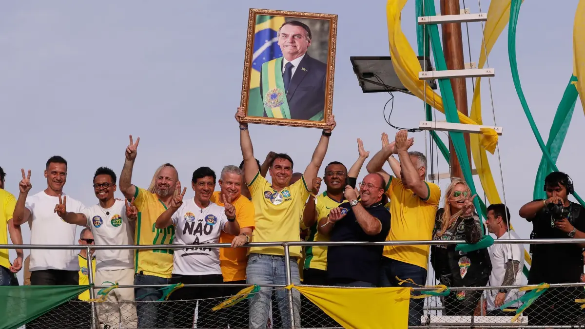 Wahlkampf in Brasilien: Der Präsidentschaftskandidat der Opposition, Flavio Bolsonaro, hält ein Foto seines Vaters, des ehemaligen Präsidenten Jair Bolsonaro, in der Hand, während er bei einer Wahlkampfveranstaltung im Vorfeld der Parlamentswahlen im Oktober auf einem Boot fährt. (zu dpa: «Kann Lula das Ruder in Brasilien noch herumreißen?»)